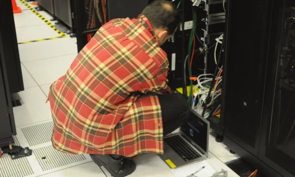 Technician working with a laptop beside server racks, representing enterprise AI retrieval infrastructure