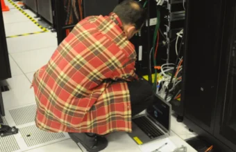Technician working with a laptop beside server racks, representing enterprise AI retrieval infrastructure