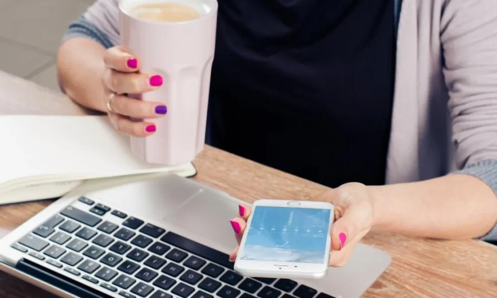 A person with a laptop and smartphone, representing digital attention and AI-assisted work