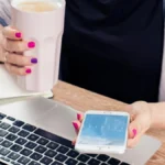 A person with a laptop and smartphone, representing digital attention and AI-assisted work