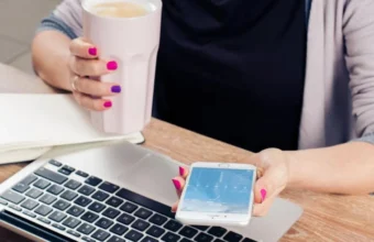 A person with a laptop and smartphone, representing digital attention and AI-assisted work