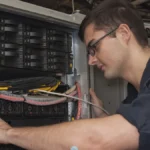Technician maintaining a server rack, representing managed security infrastructure for vulnerability triage systems