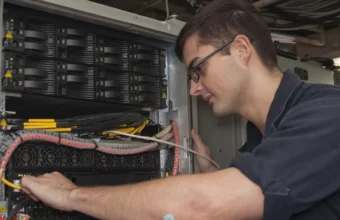 Technician maintaining a server rack, representing managed security infrastructure for vulnerability triage systems