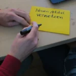 A person writes on a sticky note during a Wikimedia technical wishlist workshop, representing open source design contribution planning
