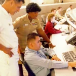 Information systems personnel studying a network operations monitor, representing Splunk incident response and vulnerability remediation