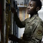 Air Force communications technician inspecting fiber optic routing in a server room, representing connection-layer reliability