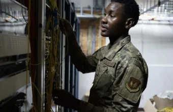 Air Force communications technician inspecting fiber optic routing in a server room, representing connection-layer reliability