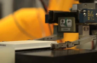 A laboratory robot arm handling an assay plate, representing low-latency remote machine control