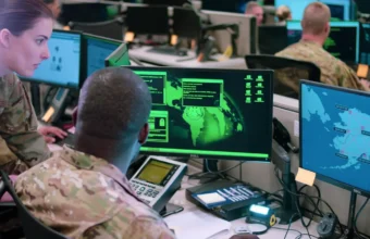 Two Air Force cyber operators work at computer monitors during a staged cyber-attack response scene