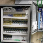 Technician testing control wiring in a transformer room, representing industrial control systems for soft real-time vPAC deployments