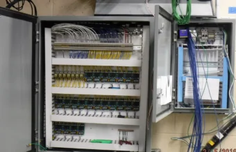 Technician testing control wiring in a transformer room, representing industrial control systems for soft real-time vPAC deployments