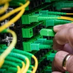 A technician connects green fiber optic cables at a data center, representing a private production inference endpoint.