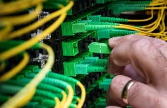 A technician connects green fiber optic cables at a data center, representing a private production inference endpoint.