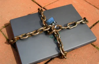 A laptop wrapped in a chain and padlock, illustrating least-privilege controls for AI agents.