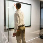 A person sketching on a whiteboard beside geometric glass patterns, representing enterprise knowledge-graph modeling and platform design.