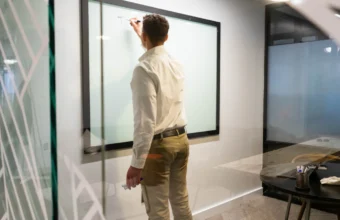 A person sketching on a whiteboard beside geometric glass patterns, representing enterprise knowledge-graph modeling and platform design.