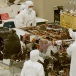 Engineers in a clean-room lab working around a robotic system, symbolizing controlled environments for AI-agent training.