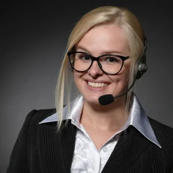 A customer-support representative wearing a headset against a dark studio background.