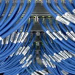 Close-up of blue Ethernet cables connected to a network switch, representing network infrastructure exposed by UniFi OS vulnerabilities.