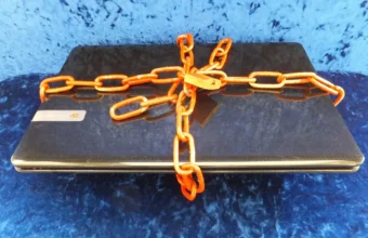 A laptop secured with a chain and padlock, symbolizing account security around encrypted messaging.