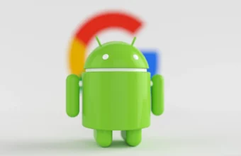 Green Android robot mascot standing in front of a blurred Google G logo, representing the Google and Epic Games Android app store antitrust case