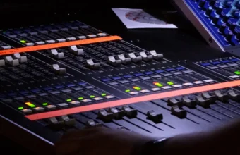 Close-up of a digital audio mixing console with many rows of sliders and channel controls