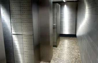 Stainless steel safe deposit boxes lining a bank vault corridor, representing secrets stored in Azure Key Vault