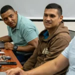 Cybersecurity training participants review security practices together at laptops during a joint exercise