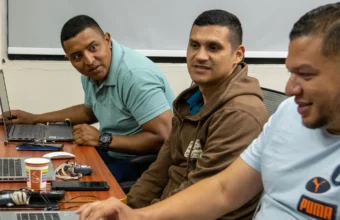 Cybersecurity training participants review security practices together at laptops during a joint exercise