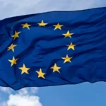 The European Union flag flying against a blue sky, representing EU AI Act jurisdiction over sovereign AI infrastructure