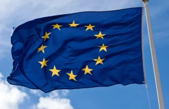 The European Union flag flying against a blue sky, representing EU AI Act jurisdiction over sovereign AI infrastructure