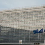 The Berlaymont building in Brussels, headquarters of the European Commission, with three European Union flags flying in front of it