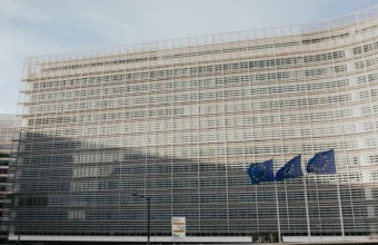 The Berlaymont building in Brussels, headquarters of the European Commission, with three European Union flags flying in front of it