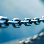 Close-up of a polished steel chain with sharp, connected links against a blue background, representing a verifiable software supply chain
