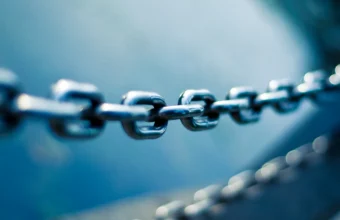 Close-up of a polished steel chain with sharp, connected links against a blue background, representing a verifiable software supply chain