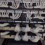 Ethernet patch panels and rack-mounted network switches with organized cabling, representing the physical version of the virtual namespaces, cables, and switch built in this tutorial