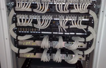 Ethernet patch panels and rack-mounted network switches with organized cabling, representing the physical version of the virtual namespaces, cables, and switch built in this tutorial