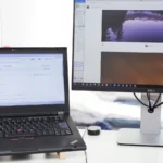 Laptop screen showing GitHub source code next to an external monitor on a clean office desk