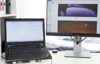 Laptop screen showing GitHub source code next to an external monitor on a clean office desk