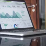 Laptop screen showing a colorful analytics dashboard with charts and graphs