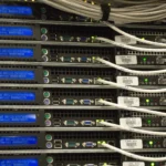 Close-up of a rack-mounted server row with blue diagnostic displays and network cables in a data center