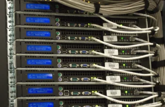Close-up of a rack-mounted server row with blue diagnostic displays and network cables in a data center