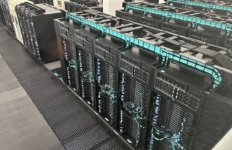 Rows of liquid-cooled supercomputer server racks with turquoise cable management at the Barcelona Supercomputing Center, representing the GPU infrastructure that LLM serving benchmarks measure