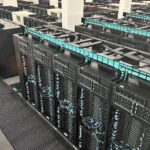 Rows of GPU accelerator server racks with turquoise cable management at the MareNostrum 5 supercomputer, Barcelona Supercomputing Center