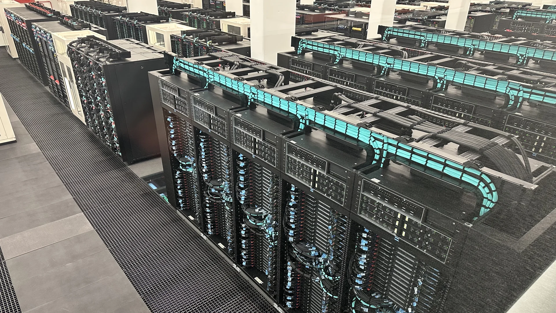 Rows of GPU accelerator server racks with turquoise cable management at the MareNostrum 5 supercomputer, Barcelona Supercomputing Center