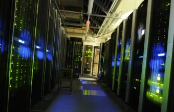 A dimly lit data center aisle with tall server racks showing blue and green status lights on both sides