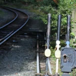 Manual railway switch levers beside diverging tracks, representing routing prompts to different AI models by complexity tier