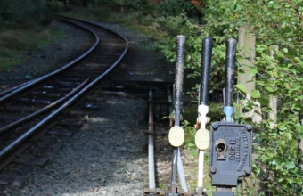 Manual railway switch levers beside diverging tracks, representing routing prompts to different AI models by complexity tier