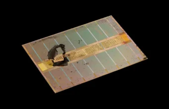 Macro photograph of an HBM DRAM memory die from an AMD Radeon RX Vega 64 graphics card, showing the dense grid of through-silicon-via contact points on the stacked memory die