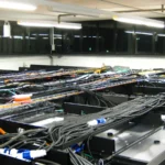 Overhead cable trays and power connectors above a row of data center server racks